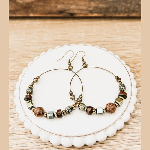 Thin metal hoop earrings decorated with wood rounds and teal stones