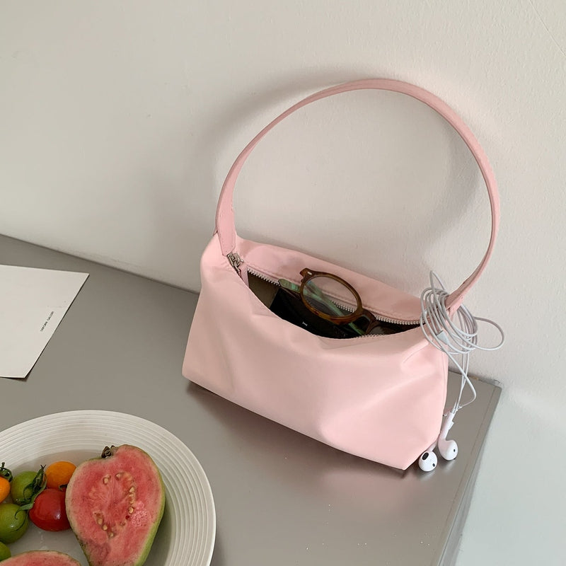 Open pink nylon shoulder bag revealing interior pocket with glasses and earphones