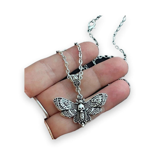 Close-up of silver geometric moth skull pendant texture in palm