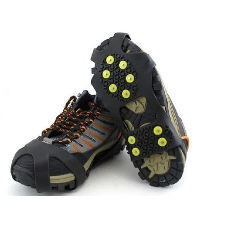 Black anti-skid crampon shoe covers with yellow traction studs on hiking shoes