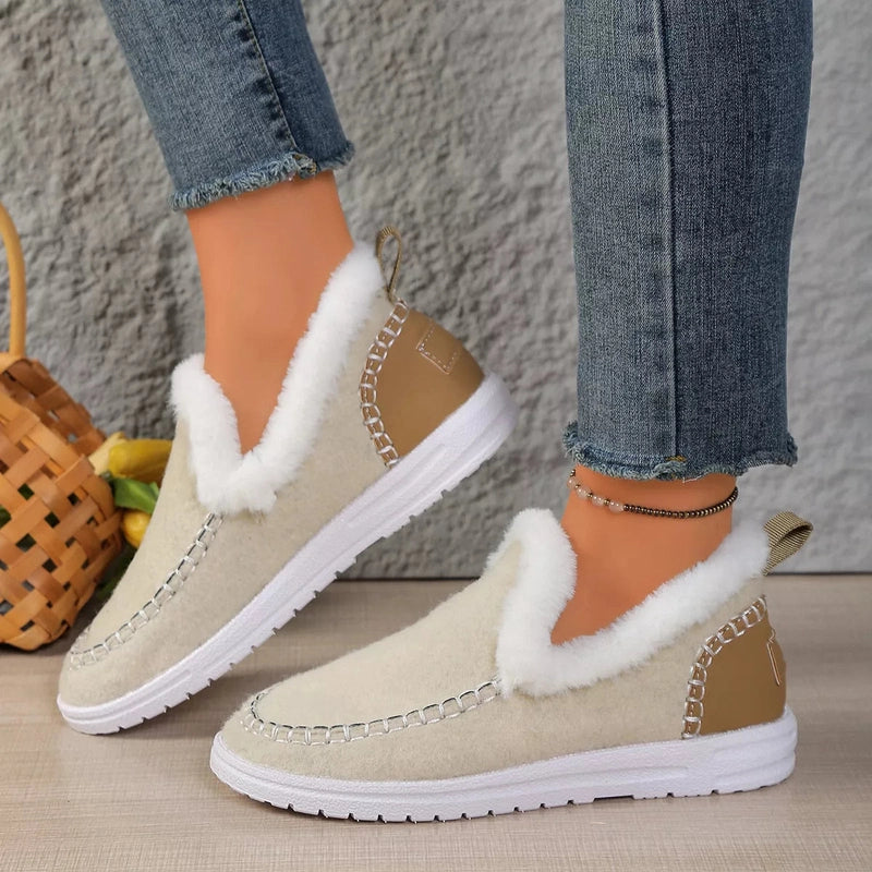 Beige plush slip-ons with white fur trim near woven basket