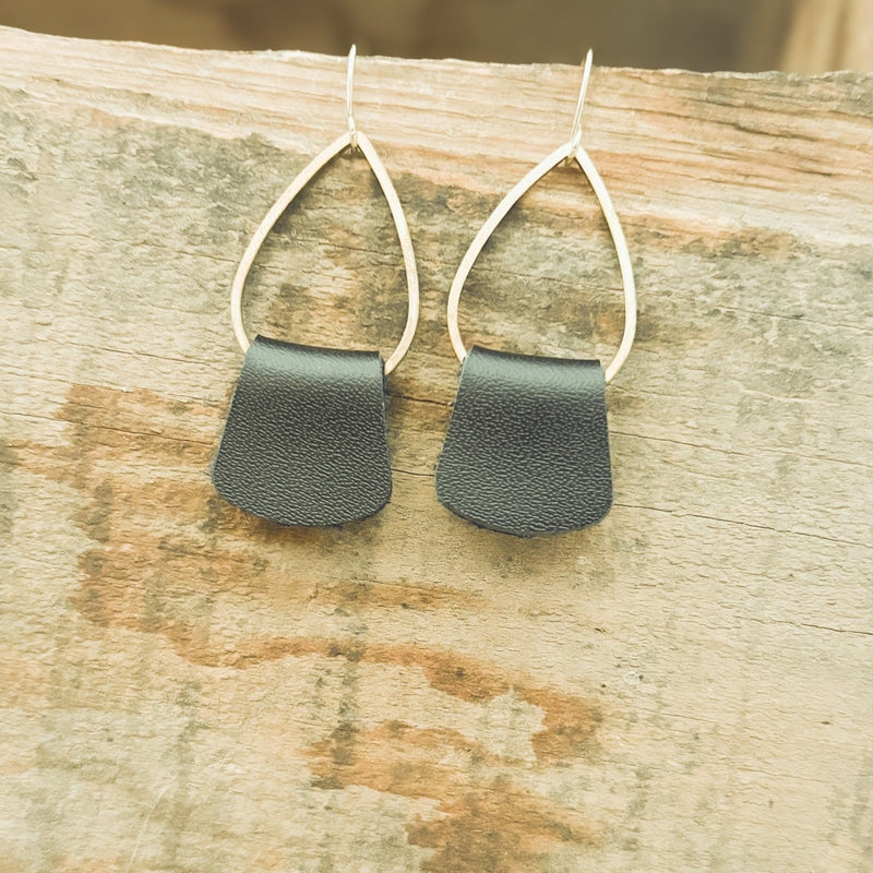 Close-up of textured black leather drop earrings with silver wire frames