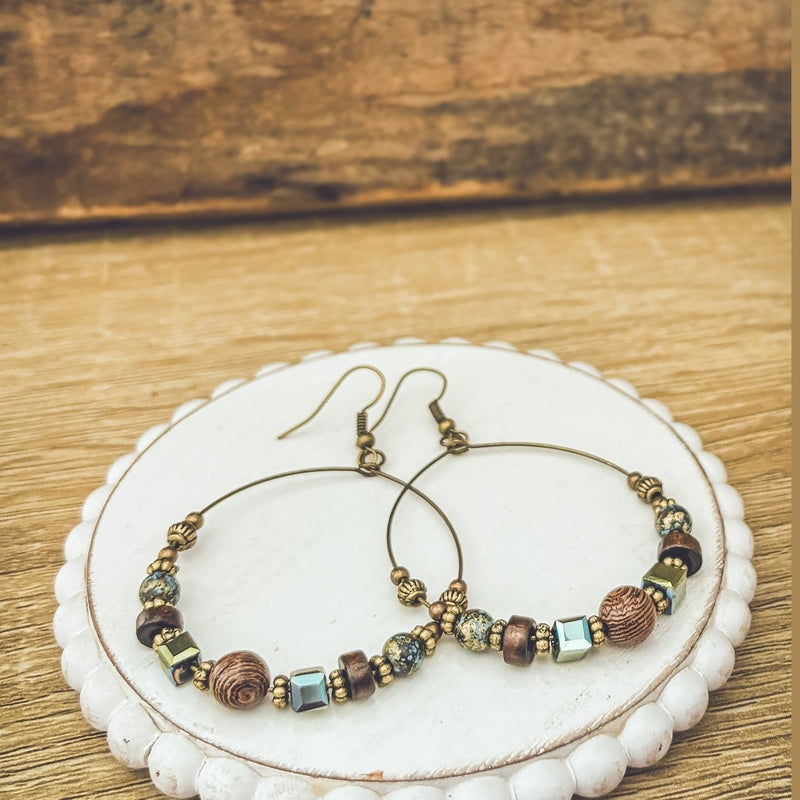 Side view of matching hoop earrings with brown, teal, and gold beads