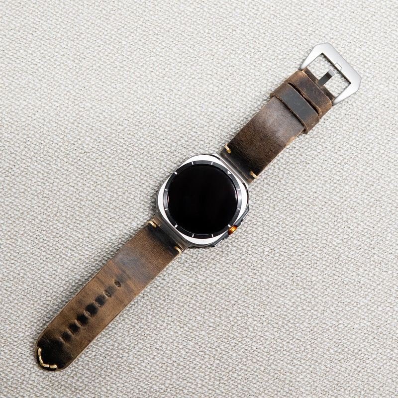 Silver smartwatch fitted with distressed brown leather strap and light stitching