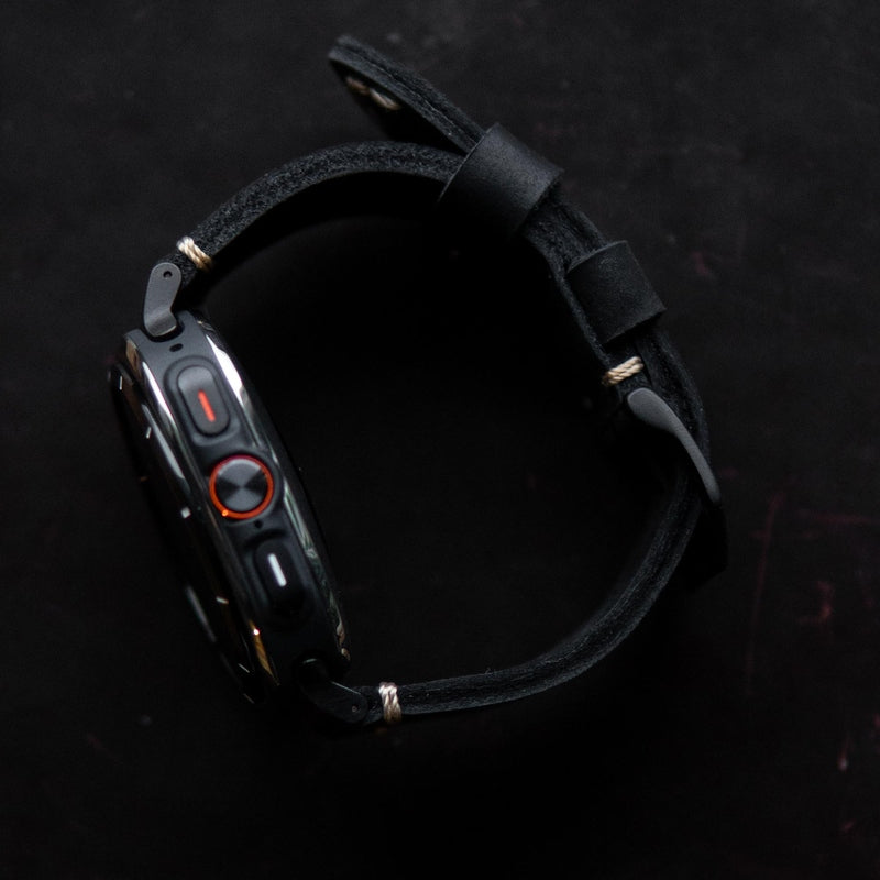Black leather watch strap looped showing matte keepers and tan edge stitching