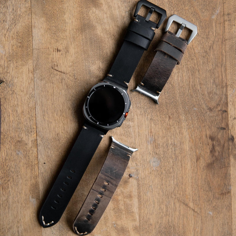 Flat lay of black and distressed brown leather watch bands with buckles