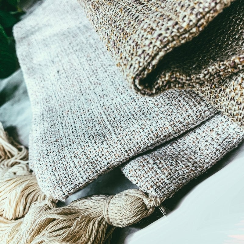 Folded speckled grey and brown cotton linen pillow cases with beige tassels
