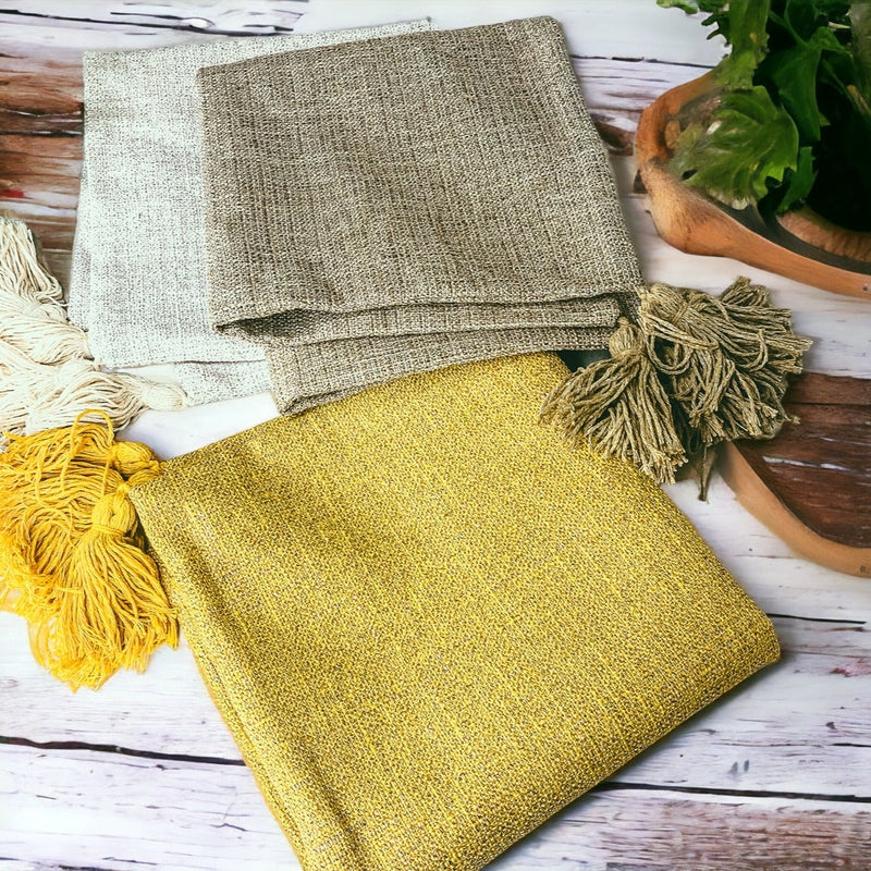 Folded mustard, taupe, and cream cotton linen pillow cases with large tassels