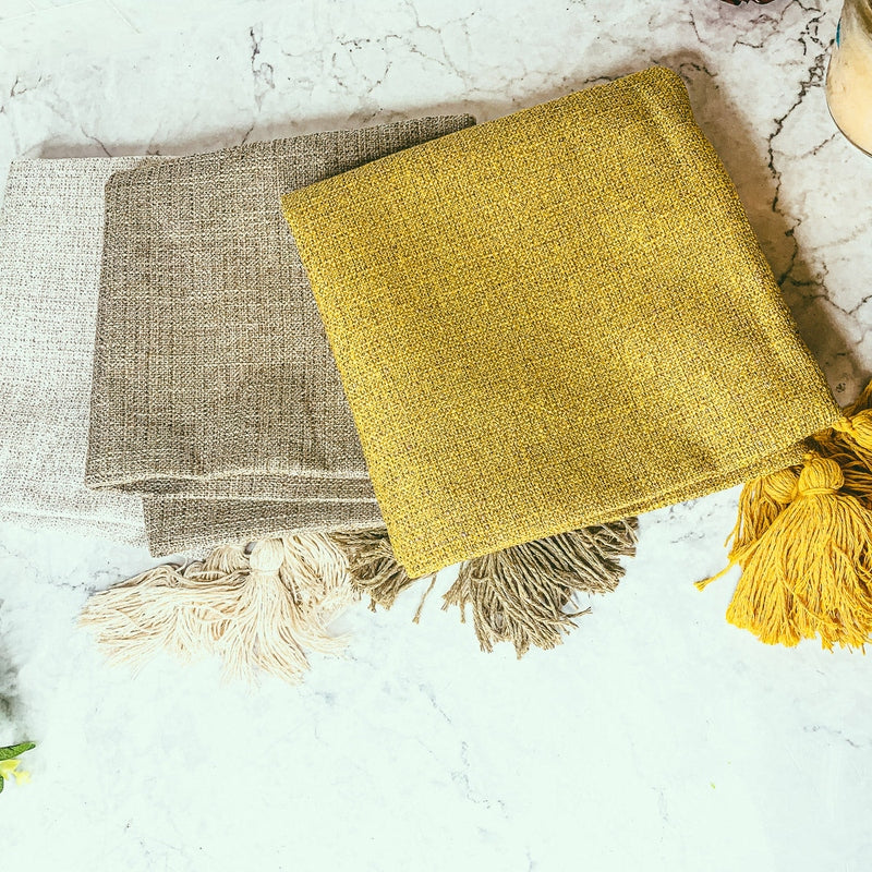 Bright yellow, brown, and beige boho pillow cases with rough texture and tassels
