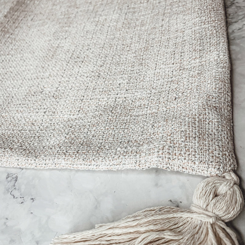 Speckled off-white cotton linen pillow case corner with cream tassel detail