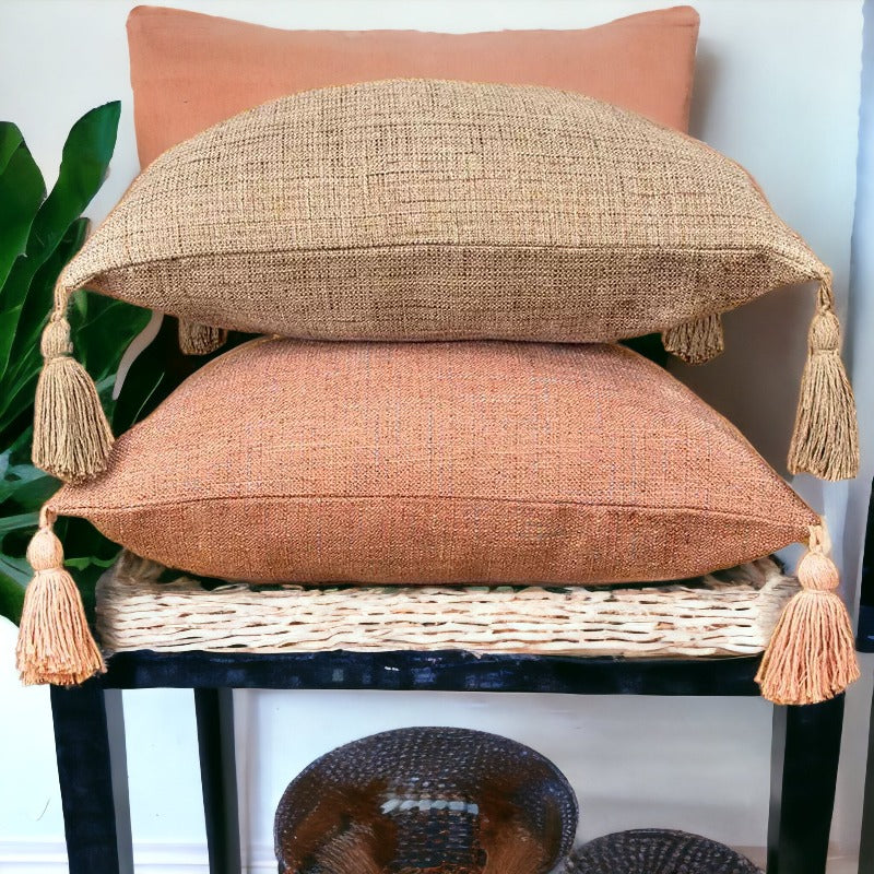 Stacked terracotta and tan cotton linen throw pillows with corner tassels