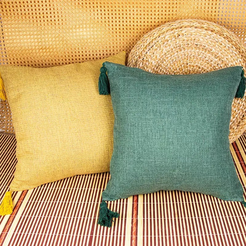 Mustard yellow and teal green throw pillow cases with tassels on bamboo mat