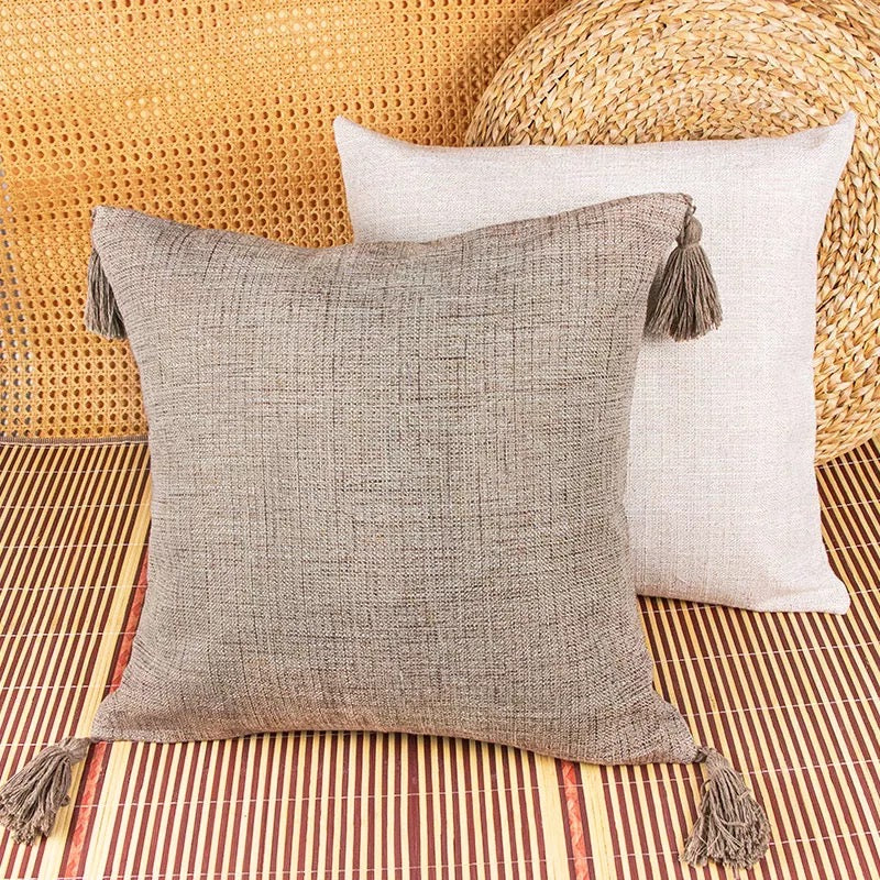 Taupe and ivory square pillow cases with corner tassels on striped mat