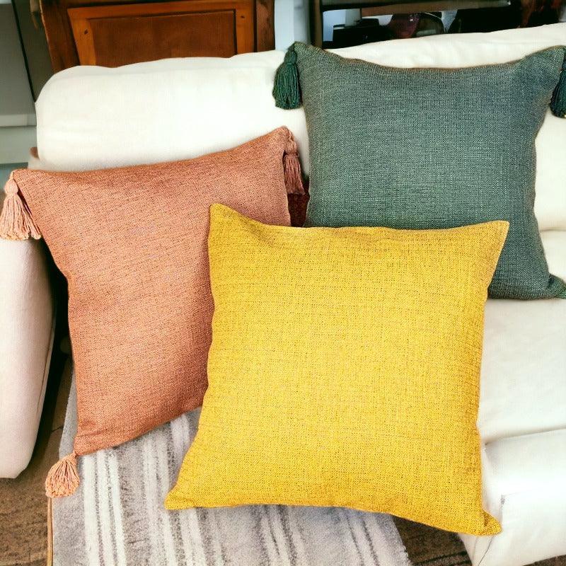 Boho cotton linen pillow cases in rust, yellow, and green with tassels on sofa