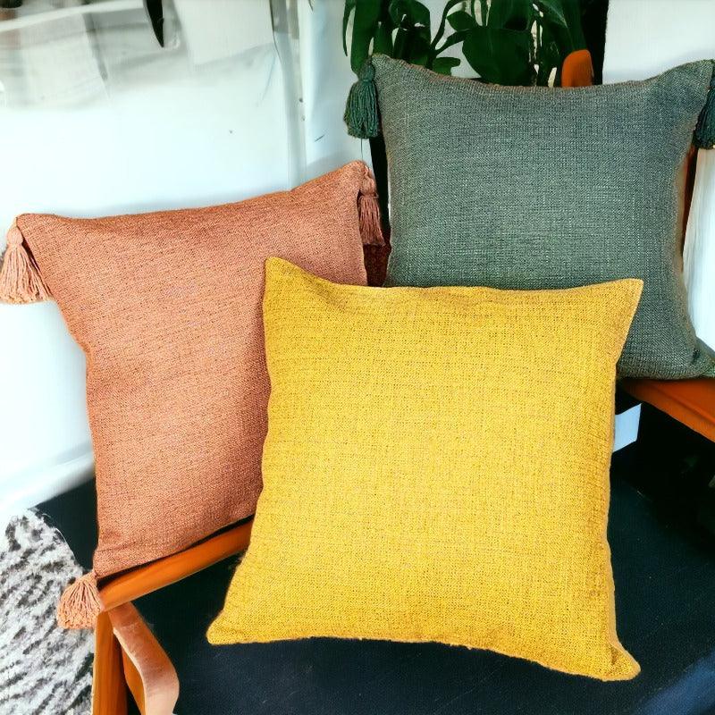 Boho terracotta, mustard, and sage green pillow cases with tassels on wooden chair