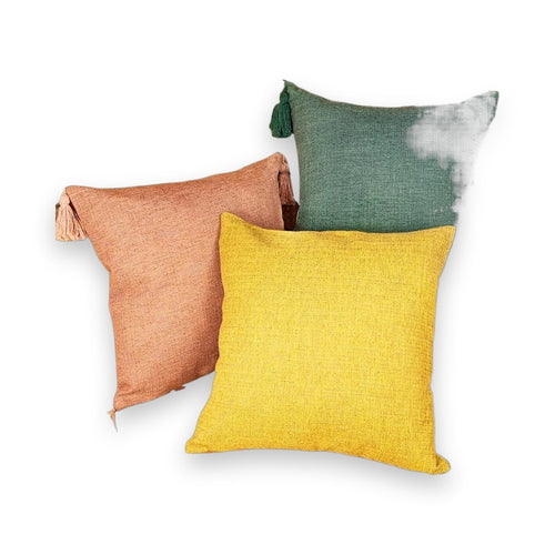 Terracotta, mustard, and sage green throw pillow cases with tassels on fuzzy blanket