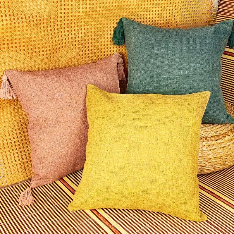 Teal, dusty rose, and mustard yellow textured cotton linen pillows on bamboo mat