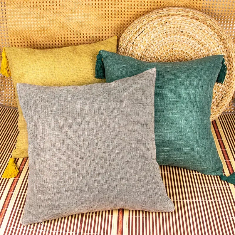Grey, mustard, and forest green textured cotton linen throw pillow covers on bamboo mat