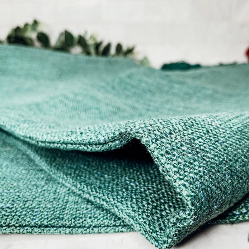 Macro shot of teal green coarse woven cotton linen fabric texture and stitching