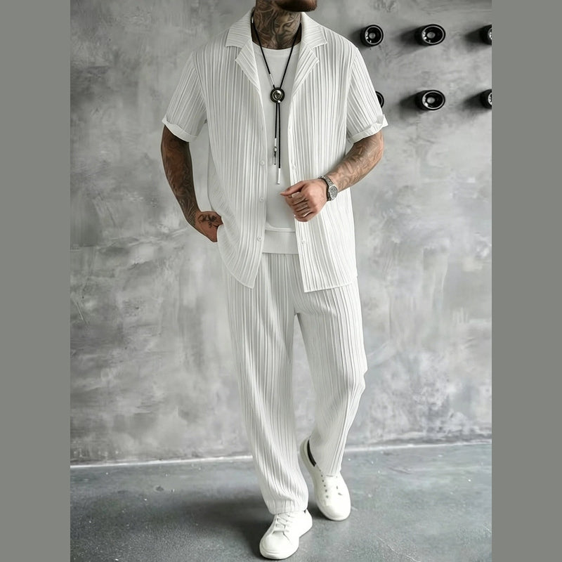 Model wearing white striped men's co-ord set with bolo tie against concrete wall