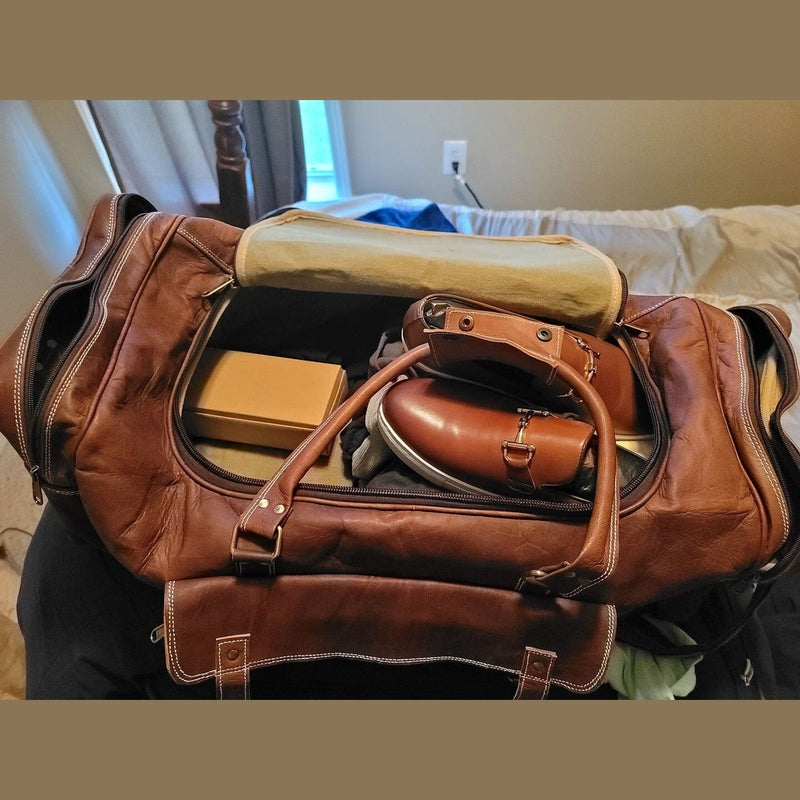 Open vintage brown leather travel duffel showing spacious beige canvas interior and packed luggage capacity