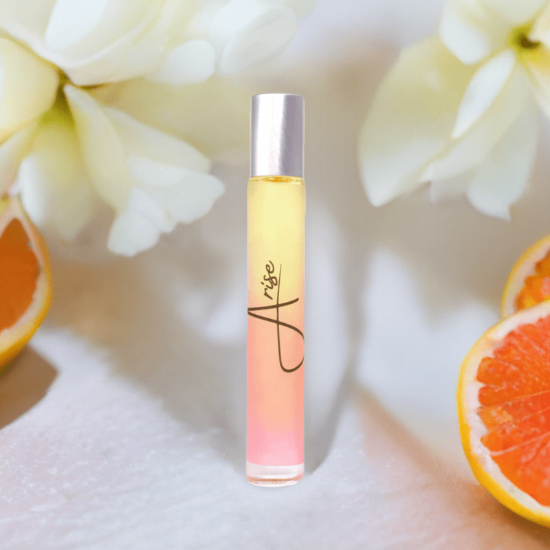 Arise floral rollerball perfume surrounded by orange slices and white flowers